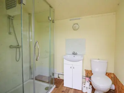 a bathroom with a shower and a toilet and a sink at Sweet Briar Shepherds Hut in Brecon
