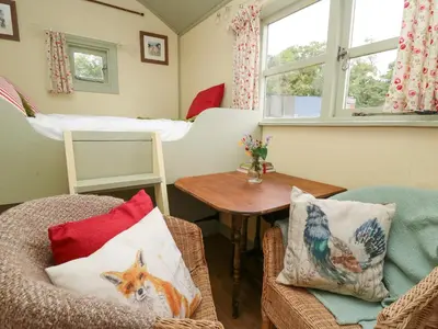 a room with a bed and a chair and a table at Sweet Briar Shepherds Hut in Brecon