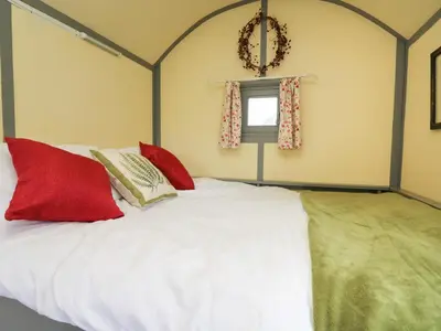 a bedroom with a white bed with red pillows at Brown Hare Shepherds Hut in Brecon