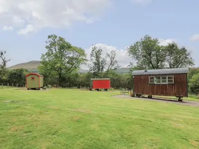 a field with two smallsheds in the middle of it at Brown Hare Shepherds Hut in Brecon