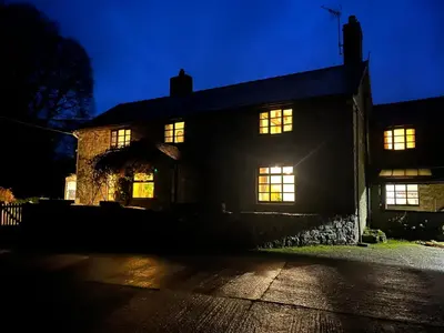 a house lit up at night with its lights on at 18th Century Farmhouse, England Wales Border, Breathtaking Views in Oswestry