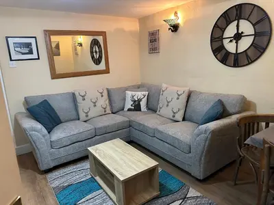 a living room with a couch and a clock on the wall at Llanidloes Townhouse-pet-friendly-sleeps 7-Mid Wales in Llanidloes
