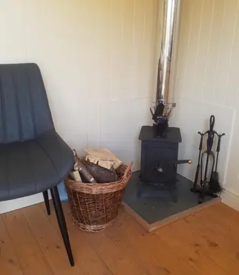 a room with a chair and a wood stove at Rhydydefaid Cwt Clyd - Cosy Hut in Bala