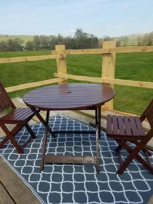 a wooden table and two chairs on a patio at Rhydydefaid Cwt Clyd - Cosy Hut in Bala
