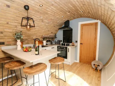 a kitchen with a table and stools in a room at Tan Y Wawr - Derwen in Welshpool