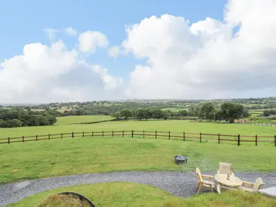 a table and chairs in a field with a fence at Tan Y Wawr - Derwen in Welshpool