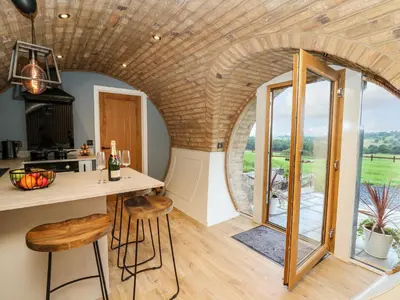 a kitchen with an arched ceiling and a table with stools at Tan Y Wawr - Derwen in Welshpool