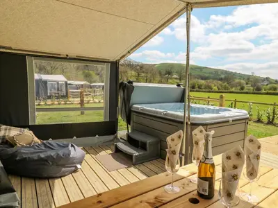 a gazebo with a hot tub and a bottle of champagne at The Salmon in Rhayader