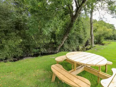 a wooden picnic table and bench in the grass at The Otter in Rhayader