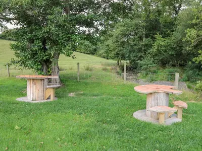 two benches and a table in the grass at The Heron in Rhayader