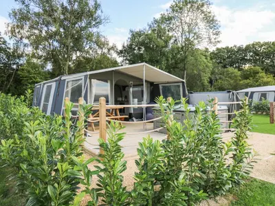 a caravan with awning and a wooden deck in a park at The Kingfisher in Rhayader