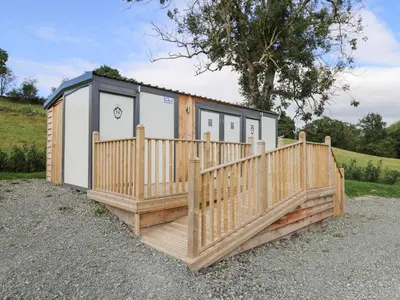 a cabin with a wooden deck and a fence at The Kingfisher in Rhayader