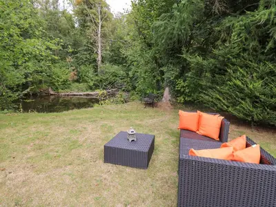 two chairs and a table with orange pillows on a yard at Riverside Rest in Builth Wells