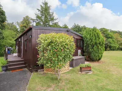 a tiny house in a garden with a tree at Riverside Rest in Builth Wells