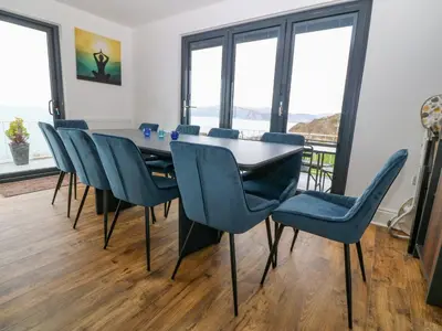 a dining room with a table and blue chairs at Machlud Haul in Llwyngwril