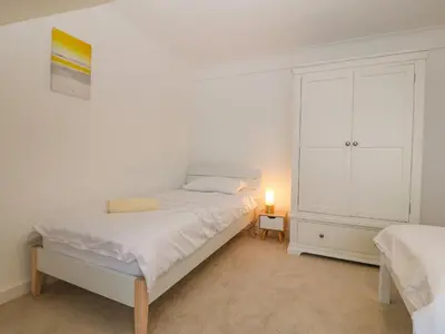 a white bedroom with a bed and a dresser at Machlud Haul in Llwyngwril