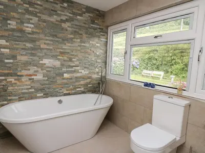 a bathroom with a tub and a toilet and a window at Machlud Haul in Llwyngwril