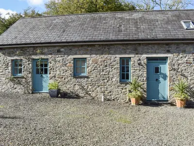a stone cottage with blue doors and potted plants at Ysgubor Blaenparc Barn - Uk41030 in Mydroilin
