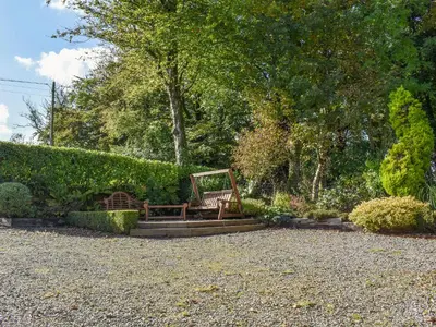 a bench sitting in the middle of a garden at Ysgubor Blaenparc Barn - Uk41030 in Mydroilin