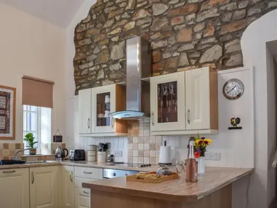 a kitchen with white cabinets and a stone wall at Ysgubor Blaenparc Barn - Uk41030 in Mydroilin
