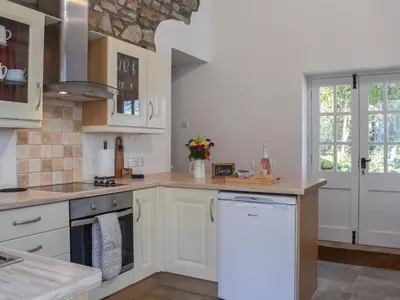 a kitchen with white cabinets and a white dishwasher at Ysgubor Blaenparc Barn - Uk41030 in Mydroilin
