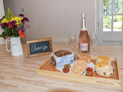 a table with a tray of bread and a bottle of wine at Ysgubor Blaenparc Barn - Uk41030 in Mydroilin