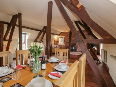 a dining room with a wooden table with flowers on it at Owlbury Hall Barn in Montgomery
