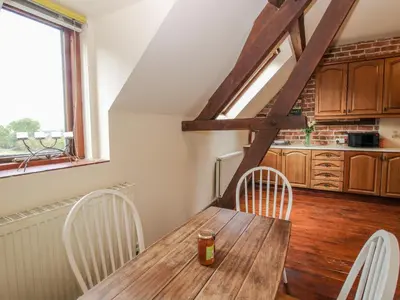 a wooden table and chairs in a kitchen with a window at Owlbury Hall Barn in Montgomery