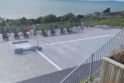 a group of benches sitting on a patio near the ocean at Barmouth Pet-Friendly 2-Bed Caravan with Sea View in Barmouth