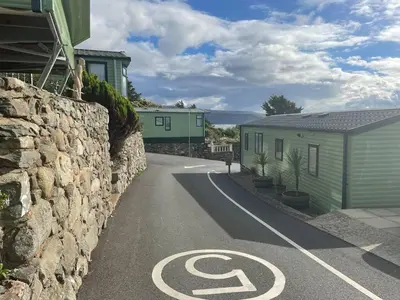 a road with a no parking sign next to a stone wall at Barmouth Pet-Friendly 2-Bed Caravan with Sea View in Barmouth