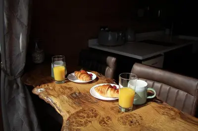 a wooden table with two plates of food and orange juice at Burrow View in Rhayader