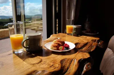 a table with a plate of food and two glasses of orange juice at Burrow View in Rhayader