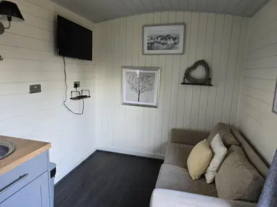 a living room with a couch and a television at Glamping Hut - Sleeps 2 hot tub & parking in Welshpool