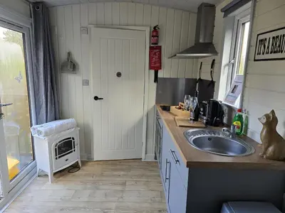 a kitchen with a sink and a cat sitting on the counter at Glamping Hut - Sleeps 2 hot tub & parking in Welshpool