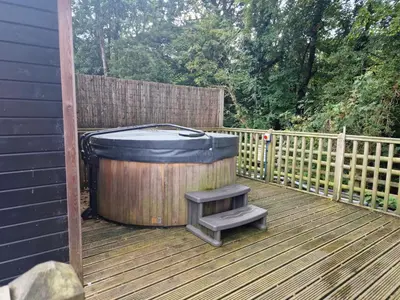 a wooden deck with a hot tub and a stool at Glamping Hut - Sleeps 2 hot tub & parking in Welshpool
