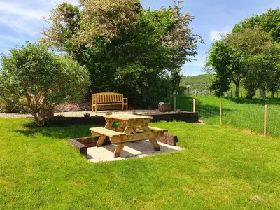 a wooden picnic table and a bench in a field at Llwynon in Aberystwyth