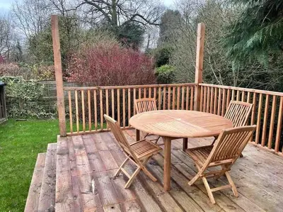 a wooden table and chairs on a wooden deck at Cwmbach Cottage, Hay on Wye in Glasbury
