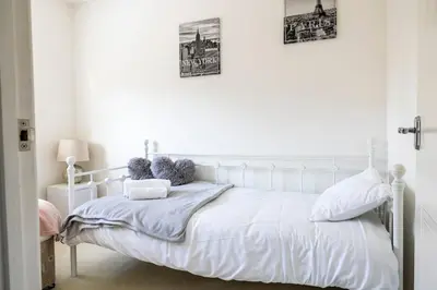 a white bed in a bedroom with two pictures on the wall at Fair View - Off Street Parking and Garden in Shrewsbury