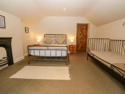 a bedroom with two beds and a fireplace at Tyn Llwyn in Talsarnau
