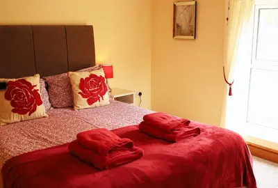 a bed with red sheets and pillows on it at Pet-Friendly Logburner Horse Stable Views in Hay-on-Wye