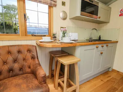 a kitchen with a counter and a chair and a sink at Poppy in Rhayader