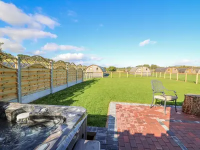 a patio with a fence and a lawn with a chair at Poppy in Rhayader