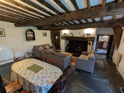 a living room with a table and couches and a fireplace at Longhouse - Hen Dy in Rhayader