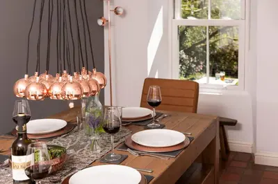 a dining room table with wine glasses and a chandelier at Charming Riverside Cottage in Snowdonia National Park in Tanygrisiau