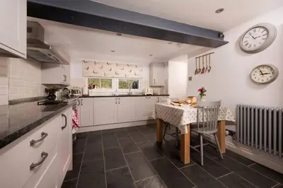 a kitchen with a table and a clock on the wall at Charming Riverside Cottage in Snowdonia National Park in Tanygrisiau