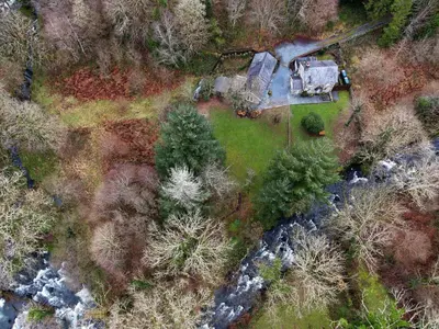 an aerial view of a house in the woods next to a river at Charming Riverside Cottage in Snowdonia National Park in Tanygrisiau
