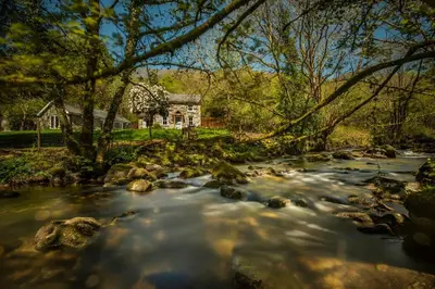 a river with rocks in front of a house at Charming Riverside Cottage in Snowdonia National Park in Tanygrisiau