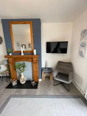 a living room with a mirror and a chair at Tywyn seaside apartment with Mountain View in Tywyn