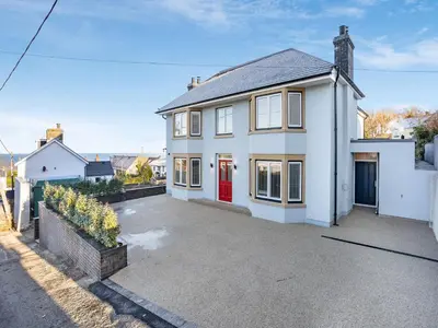 a white house with a red door at Dau Ddeg in New Quay