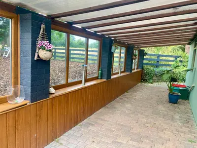 a covered walkway with windows and a basket of flowers at Mountain View Cottage, Hot Tub , Stunning Views in Llanhamlach